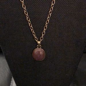 Necklace with purple medallion.